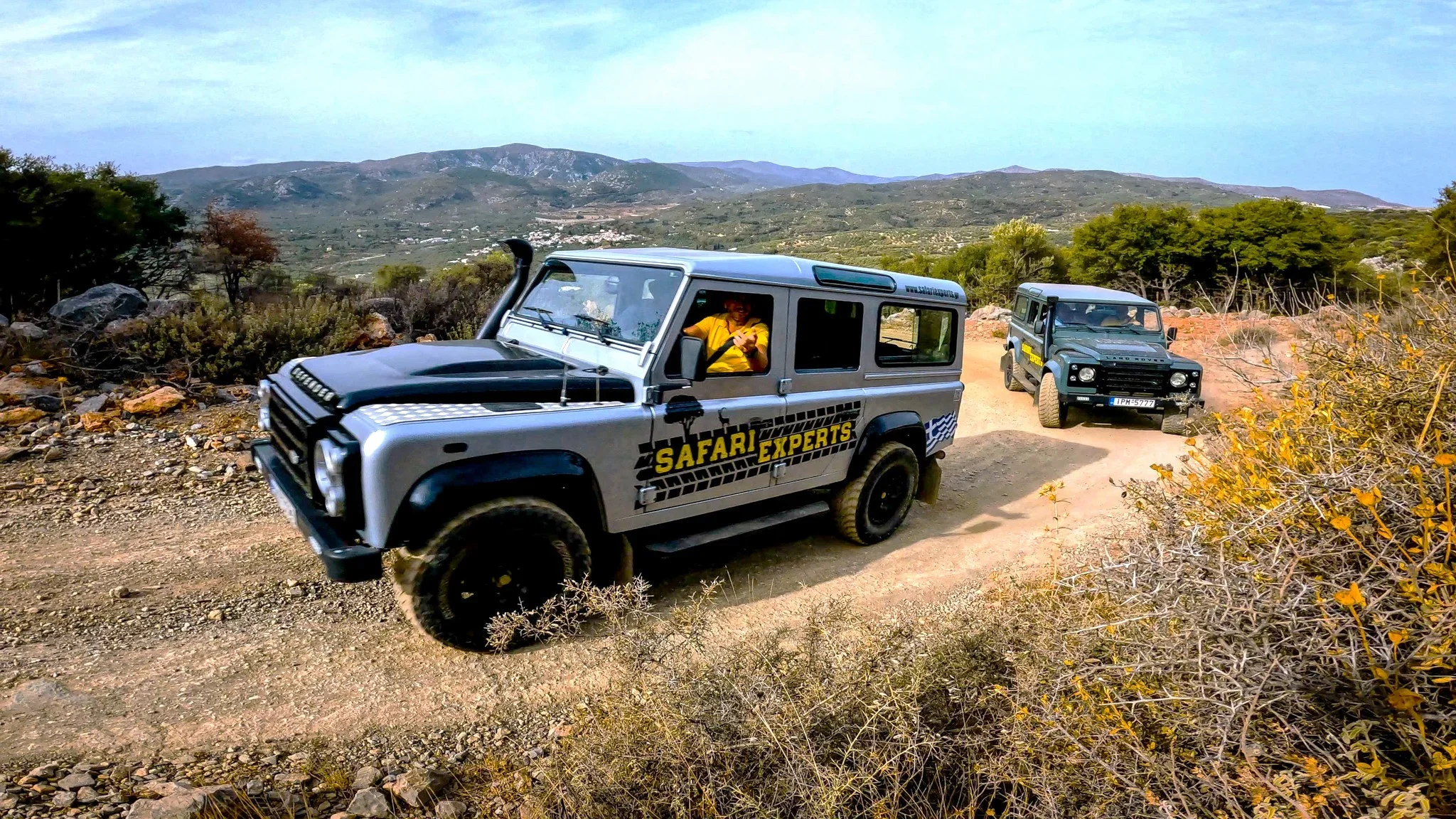 Convoy of off-road jeeps crossing the Lasithi Plateau past stone windmills
