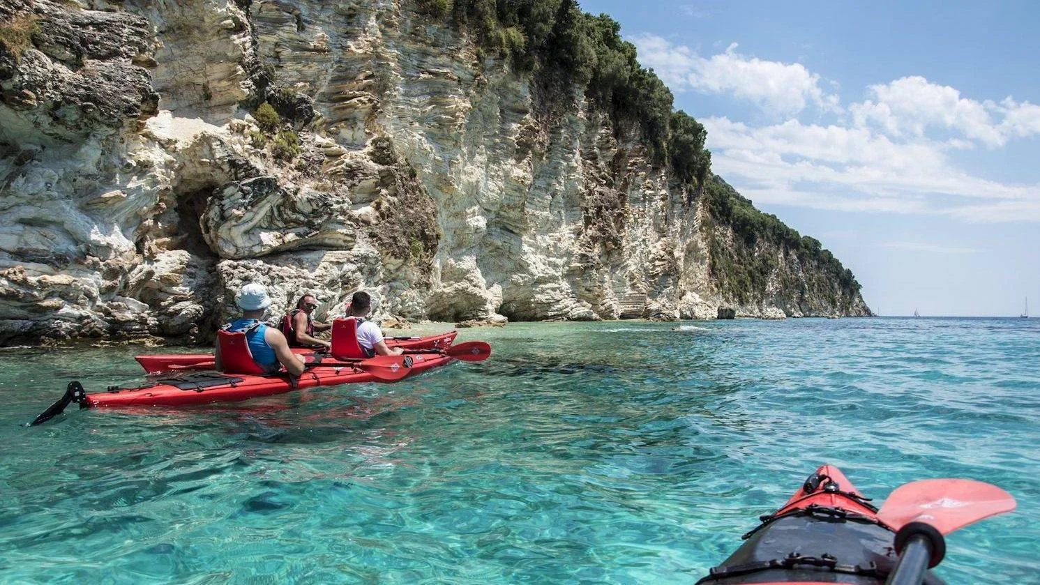 Sea kayakers paddling along the rocky coastline east of Plakias Bay