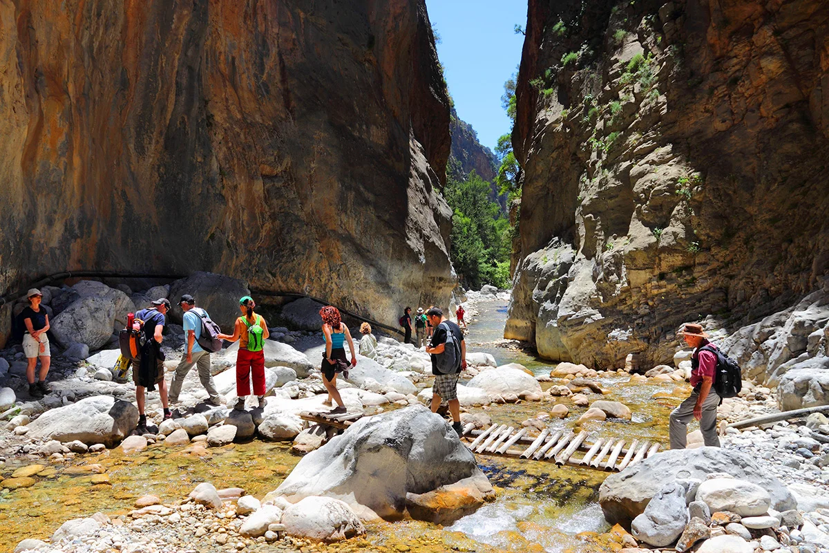 Hikers walking through the narrow rocky passage of Samaria Gorge in the White Mountains of western Crete.