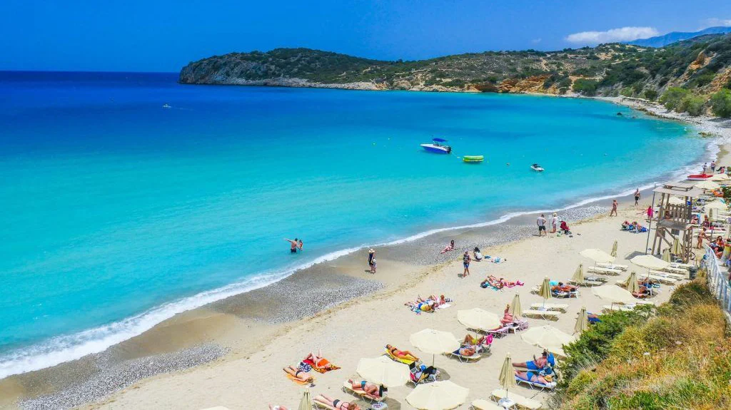 Voulisma Beach Crete, turquoise water and white sand with sunbeds, aerial view of the bay